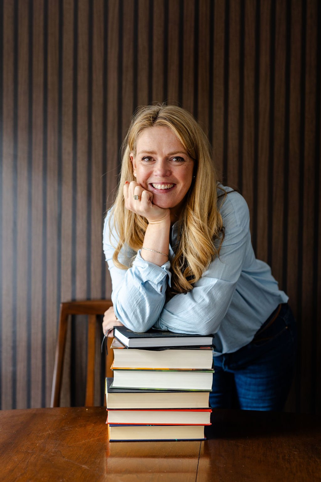 Becky Wash CEO of Crafting from Scratch is leaning her elbow on a pile of books whilst casually resting her chin on her hand