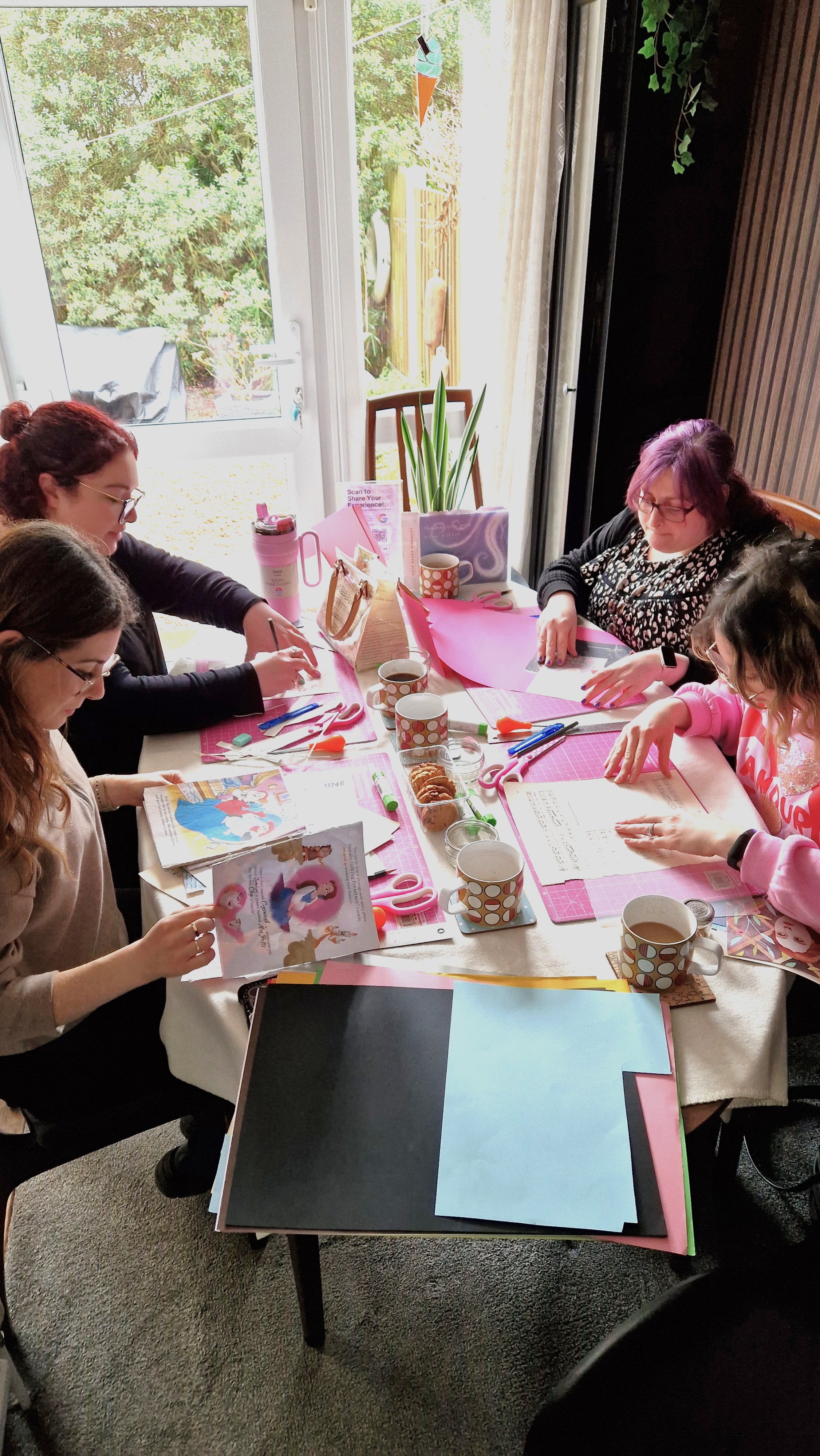 A group of women in their 30s sitting around a table crafting for a birthday party